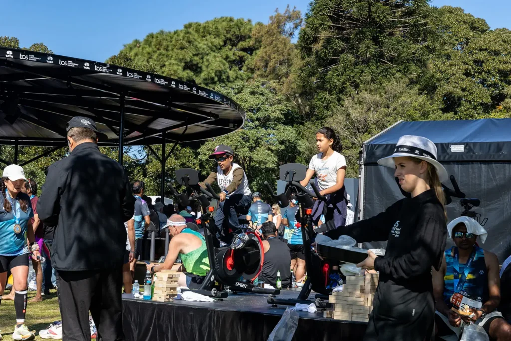 Two People Use the Exercise Bike in Front of the Sydney Harbour Bridge at Tata Consultancy Services TCS Sydney Marathon 2026, Sydney - Peanut Productions Event Management Case Study