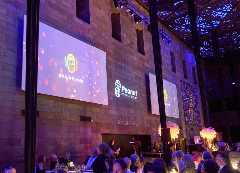 Brainwave gala in Gandel Hall with Peanut Productions logo projected on the stone wall between Brainwave screens