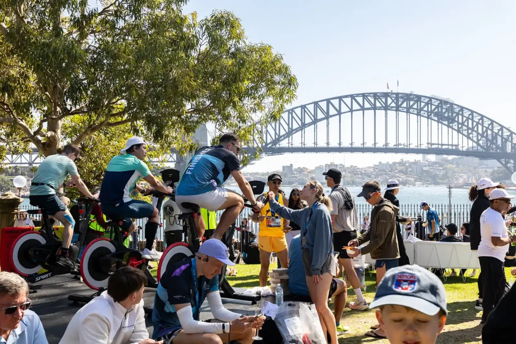 Two People Use the Exercise Bike in Front of the Sydney Harbour Bridge at Tata Consultancy Services TCS Sydney Marathon 2026, Sydney – Peanut Productions Event Management Case Study